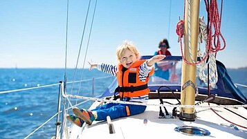 Ein Kind auf einem Segelboot auf dem Forggensee im Allgäu.