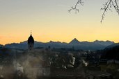 Sonnenaufgang über Nesselwang mit Kirchturm und Bergkulisse nahe dem Familienhotel Bavaria.