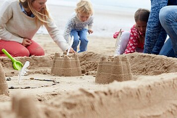 Eine Familie baut Sandburgen am Ostseestrand am Familienhotel Strandkind