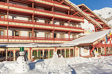 Winteransicht mit einem Schneemann auf das Familienhotel Kaiserhof an der Tiroler Zugspitzarena.