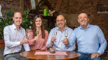 Die Gastgeber im Familienhotel Ottonenhof fröhlich mit Sektgläsern an.