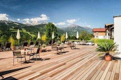 Die Sonnenterrasse des Familienhotels Ramsi in Kärnten mit gemütlichen Sitzgelegenheiten und traumhaftem Panoramablick auf die umliegenden Berge