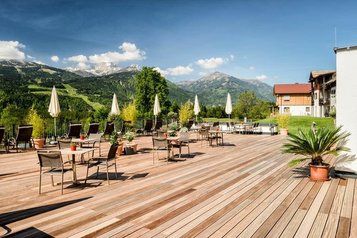 Die Sonnenterrasse des Familienhotels Ramsi in Kärnten mit gemütlichen Sitzgelegenheiten und traumhaftem Panoramablick auf die umliegenden Berge
