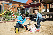 Vater spielt mit seinen beiden Kindern im auf dem Außenspielplatz des Familienhotels Schreinerhof im Bayerischen Wald.