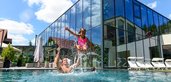 Familie planscht im großen Outdoor-Pool des Familienhotels Ulrichshof im Bayerischen Wald.