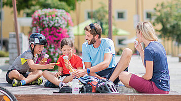 Familie sitzt beim Eis essen auf einem öffentlichen Platz in der Stadt.