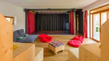 Bunte Bühne mit gemütlichen Sitzmöglichkeiten für kleine und große Auftritte im Familienhotel Ramsi