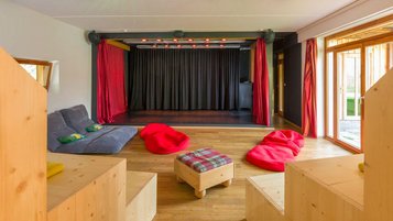 Bunte Bühne mit gemütlichen Sitzmöglichkeiten für kleine und große Auftritte im Familienhotel Ramsi