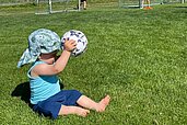 Kleiner Junge sitzt in der Wiese des Familienhotels Der Böhmerwald und spielt mit einem Fußball.