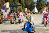 Mehrere Kinder flitzen mit Gokarts und Rutschfahrzeugen über den Hof im Familienhotel Ramsi in Kärnten