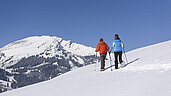 Ein Paar wandert am Berg im Schnee. Die Landschaft in Tirol im Winter ist gänzlich unberührt.