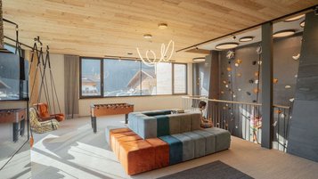 Die stylische Teens Lounge im Familienhotel lädt mit Kletterwand, Schaukelsessel und Tischfußball zu entspannten und actionreichen Momenten ein.