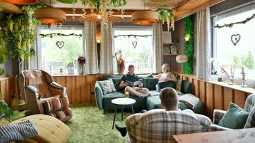 Gemütlicher Lounge-Bereich im Familienhotel Rhön Feeling mit Naturdeko, grünem Teppich und großen Fensterfronten zum Entspannen für Erwachsene.