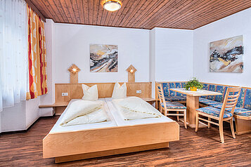 Familienzimmer mit einem Doppelbett und einem Wohnzimmer im Familienhotel Kinderhotel Sailer in Pitztal.
