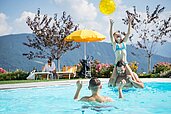 Familie im Außenschwimmbad des Hotels Family Home Alpenhof in Südtirol.