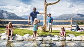 Eine Familie an einem erfrischenden Wasserspielplatz im Zirbenpark am Hochzeiger.