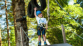 Glücklicher Junge auf dem Waldspielplatz des Spa- & Familien-Resorts Krone im Allgäu.