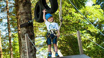 Glücklicher Junge auf dem Waldspielplatz des Spa- & Familien-Resorts Krone im Allgäu.