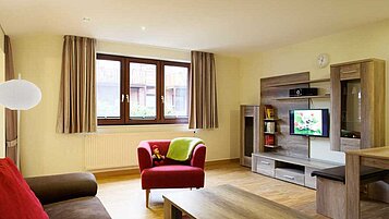 Der Wohnbereich mit Sofa, Sessel und TV im Familienzimmer im Familienhotel Landhuus Laurenz im Münsterland.
