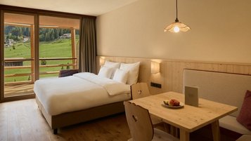 Helles Familienzimmer mit Balkon und Bergblick im Familienhotel Bella Vista in Südtirol.