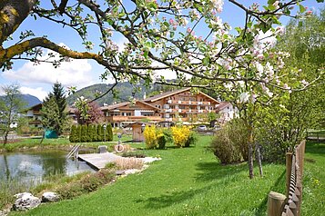 Sommeraufnahme der Liegewiese am Naturpool des Familienhotels Landgut Furtherwirt in Tirol.