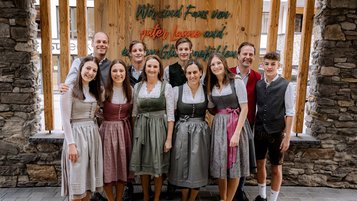 Die Gastgeberfamilie des Familienhotels Zauchenseehof in traditioneller Tracht vor dem Hoteleingang.