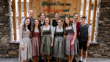 Die Gastgeberfamilie des Familienhotels Zauchenseehof in traditioneller Tracht vor dem Hoteleingang.