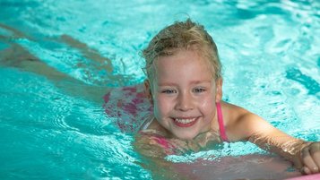 Glückliches Mädchen schwimmt im Pool des Familienhotels Gut Landegge im Emsland.