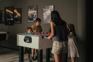 Kinder spielen lachend Tisch-Kicker mit gleichaltrigen in ihrem Urlaub im Familienhotel Engel Gourmet & Spa in Südtirol