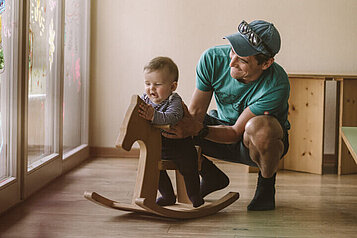 Vater spielt mit seine Kleinkind im Babyspielbereich des Familienhotels Tirolerhof in Tirol.