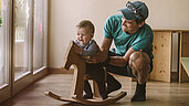 Vater spielt mit seine Kleinkind im Babyspielbereich des Familienhotels Tirolerhof in Tirol.