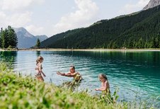 Eine Familien geht in einem Bergsee schwimmen.