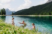 Eine Familien geht in einem Bergsee schwimmen.