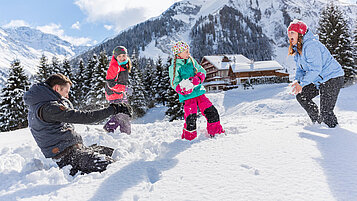 Familie tobt im Schnee im Familienurlaub im Familienhotel Kaiserhof in Tirol.