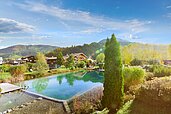 Luftaufnahme von Landschaft und Naturpool des Familienhotels Landgut Furtherwirt in Tirol.