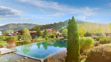 Luftaufnahme von Landschaft und Naturpool des Familienhotels Landgut Furtherwirt in Tirol.