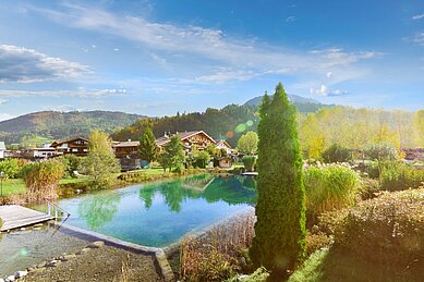 Luftaufnahme von Landschaft und Naturpool des Familienhotels Landgut Furtherwirt in Tirol.