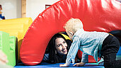 Kinderbetreuerin spielt gemeinsam mit Kleinkind im Happy-Club