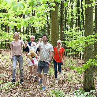 Eine Familie mit Oma und Opa beim Spaziergang durch einen Wald