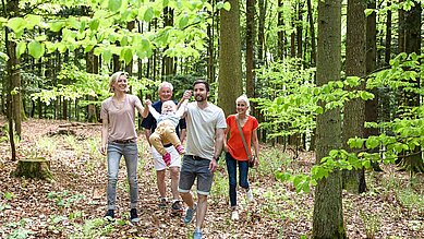 Eine Familie mit Oma und Opa beim Spaziergang durch einen Wald