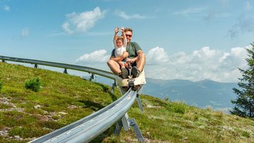 Vater und Tochter auf der Sommerrodelbahn in Kärnten bei schönem Wetter
