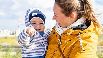 Mutter mit Baby am Strand an der Nordsee im Familienurlaub an der Nordsee.