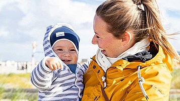 Mutter mit Baby am Strand an der Nordsee im Familienurlaub an der Nordsee.