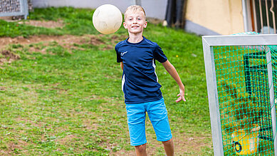 Teenager spielt im Garten des Familienhotels Engel im Schwarzwald Fußball.