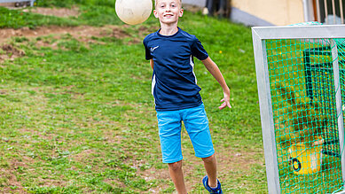 Teenager spielt im Garten des Familienhotels Engel im Schwarzwald Fußball.