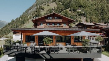 Sonnige Terrasse des Familienhotels Oberkarteis mit modernen Sitzbereichen und Blick auf die umliegenden Berge im Salzburger Land.