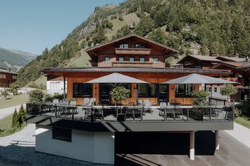 Sonnige Terrasse des Familienhotels Oberkarteis mit modernen Sitzbereichen und Blick auf die umliegenden Berge im Salzburger Land.