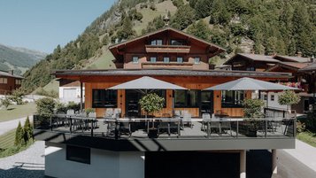 Sonnige Terrasse des Familienhotels Oberkarteis mit modernen Sitzbereichen und Blick auf die umliegenden Berge im Salzburger Land.