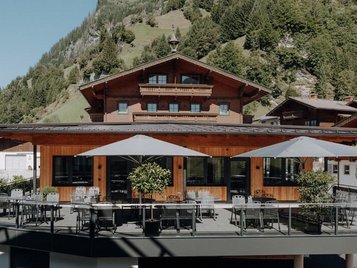 Sonnige Terrasse des Familienhotels Oberkarteis mit modernen Sitzbereichen und Blick auf die umliegenden Berge im Salzburger Land.