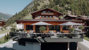 Sonnige Terrasse des Familienhotels Oberkarteis mit modernen Sitzbereichen und Blick auf die umliegenden Berge im Salzburger Land.